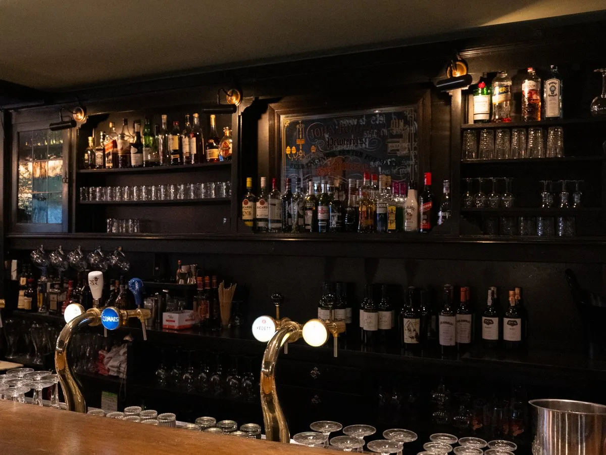 De houten bar met tapkranen en een wand vol flessen